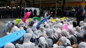 Demonstration mit Schlauchbooten und weißen Plastik-Schutzanzügem gegen die Identitären