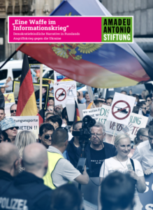 Menschen sind auf einer Demonstration, sie halten Schilder hoch mit Kameras, die durchgestrichen sind und Deutschland und Russlandflaggen. Oben steht: »Eine Waffe im Informationskrieg« Demokratiefeindliche Narrative in Russlands Angriffskrieg gegen die Ukraine. Rechts daneben: Amadeu Antonio Stiftung.